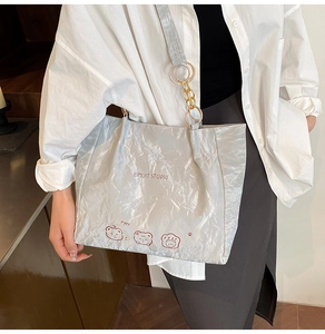 Detail of silver metallic tote bag featuring gold ring chain and cute bear print pattern