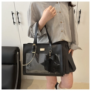 Detail of black tote bag with transparent PVC window and gold chain bow ornament