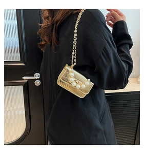 Vue détaillée d'un sac doré à motif crocodile avec boucle en perles et bandoulière chaîne
