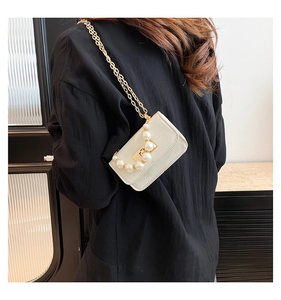 Détail du mini sac blanc embossé crocodile avec une poignée élégante en grosses perles