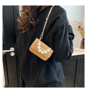 Détail du mini sac marron clair avec motif crocodile, poignée en perles et chaîne dorée