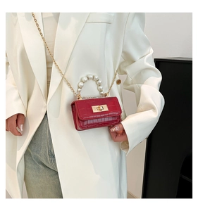 Détail du sac rouge à motif crocodile avec poignée en perles et chaîne dorée