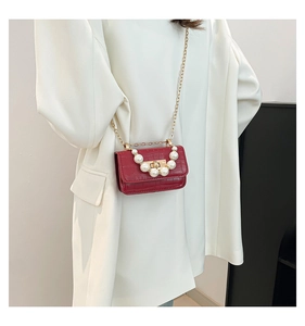 Mini sac rouge avec motif crocodile, poignée en perles et chaîne dorée sur blazer blanc