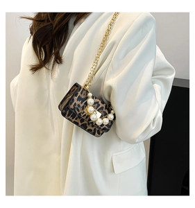 Mini sac léopard chic avec poignée en perles et chaîne dorée porté par un mannequin