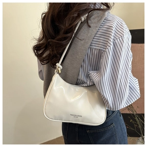 Close-up of a white leather hobo bag worn with a striped shirt and blue jeans