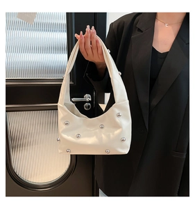 Detail of off-white PU leather hobo bag with silver ball studs held by a model