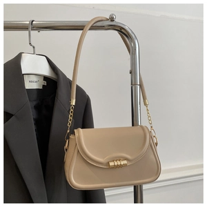 Detail of a cream leather handbag with gold buckle clasp hanging on a metal hanger