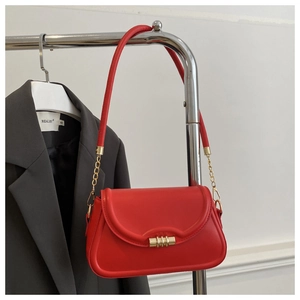 Detailed shot of vibrant red shoulder bag with gold clasp and textured flap design