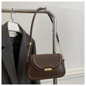 Detail of dark brown leather crossbody bag with gold twist lock and chain strap on hanger