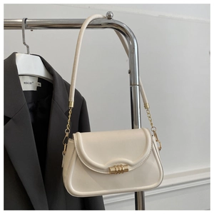 Detail of cream white shoulder bag with gold metal cylinder buckle and leather chain strap