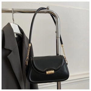 Detail of black leather underarm bag with gold metal buckle and chain strap on grey blazer