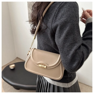 Detail of beige structured shoulder bag with iconic gold hardware and chain strap