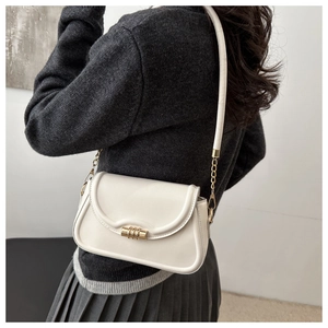Detail of a beige PU leather shoulder bag with gold hardware on a model's back