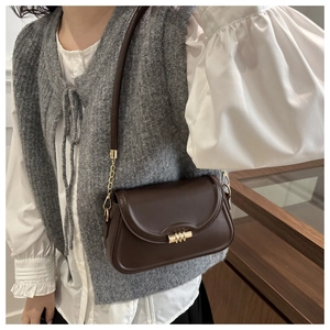Detail of vintage brown crossbody bag with gold lock and chain strap on a model