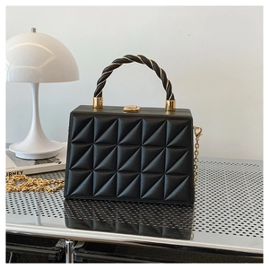 Detailed close-up of black geometric embossed box bag with gold chain and twisted handle