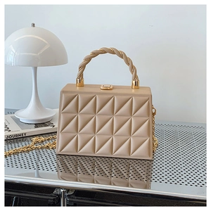 Detail of beige geometric quilted box bag with spiral handle and gold chain strap