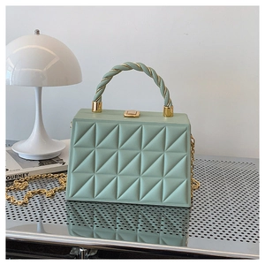 Detail of mint green box bag with geometric quilting and metallic twisted handle