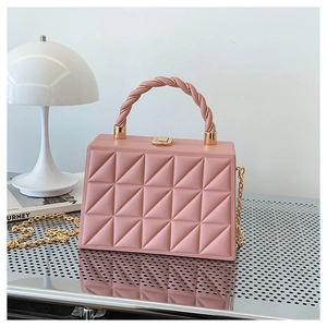 Close-up of pink geometric quilted box bag with a twisted handle and gold chain