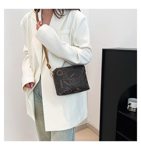 Detail of vintage printed crossbody bag in dark brown on a model wearing white blazer