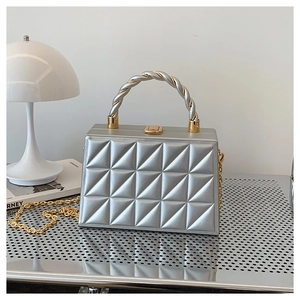 Detail of silver trapezoid evening bag with quilted texture and twist metal handle