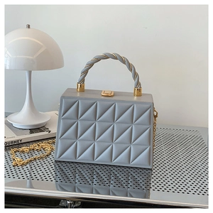 Detail of grey geometric quilted handbag with gold chain strap and textured handle