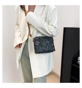 Détail du sac cabas noir imprimé avec bandoulière en cuir marron et crochets dorés