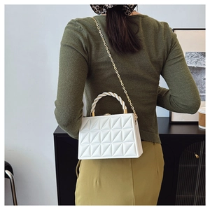 Detail of white box bag featuring 3D geometric quilting and gold chain strap