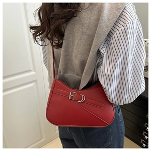 Detalle de bolso de hombro rojo de media luna con hebilla plateada llevado por modelo