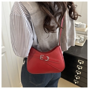 Detalle de un bolso de hombro de cuero rojo en forma de medialuna con hebilla plateada