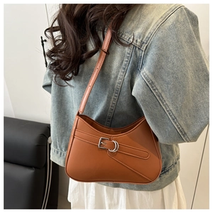 Detalle de bolso de hombro color caramelo con cinturón decorativo usado por modelo
