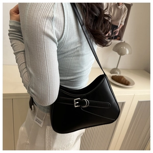 Close-up of minimalist black leather baguette bag with silver buckle and metal rings