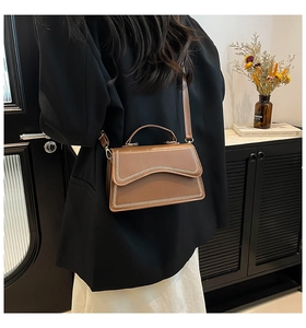 Close-up of brown leather bag featuring off-white V-shaped woven stitching details