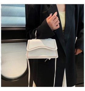 Detail of white leather shoulder bag with brown contrast stitching and long strap