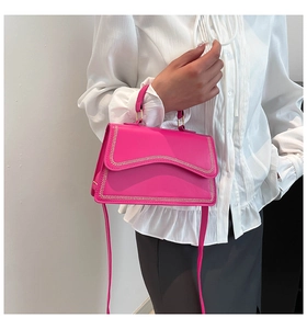 Detail of fuchsia trapezoid handbag featuring a unique metallic wave-patterned flap