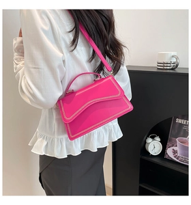 Close-up of rose pink crossbody bag with wavy stitching and slim shoulder strap