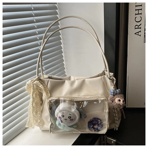 Close-up of cream PU leather tote bag featuring a clear window with plush accessories