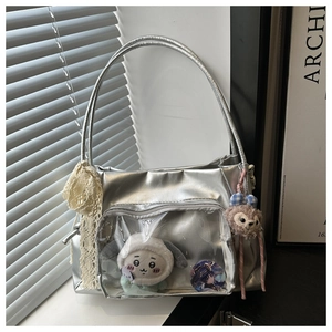 Detail of silver ita bag with transparent PVC window and decorative character charms