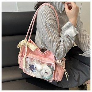 Detail view of pink ita bag with transparent window, lace bow and plush charms