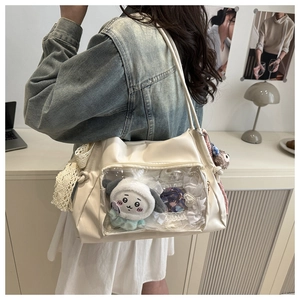 Detail of cream messenger bag with transparent window showing plush toy and lace decor