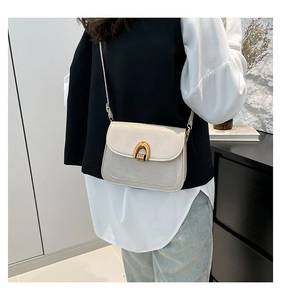 Detail of off-white minimalist crossbody bag with gold arch metal buckle on a model