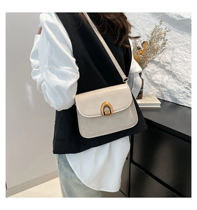 Detail of a beige PU leather saddle bag with a gold U-shaped buckle on a fashion model