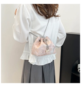 Détail du sac seau en soie rose avec broderie florale et pendentifs en perles