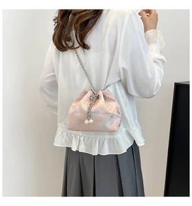 Détail du sac seau en jacquard rose avec cordon perlé et bandoulière chaîne