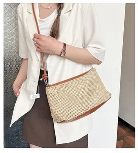 Detail of straw woven crossbody bag with brown leather trim and adjustable shoulder strap