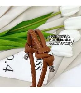 Detail of a brown leather shoulder strap with knotted design and fine white stitching