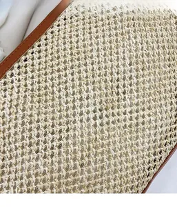 Close-up of hand-woven straw tote bag showing fine texture and brown leather trim