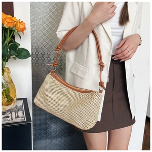 Detail showing handwoven straw texture and brown leather knotted shoulder strap
