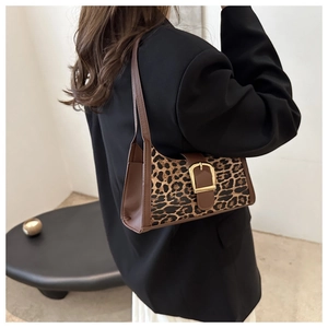 Dettaglio borsa sottobraccio leopardata con finiture in pelle marrone e fibbia dorata