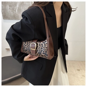 Détail du sac baguette léopard avec bandoulière en cuir marron et boucle dorée chic