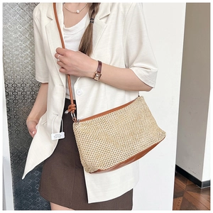 Close-up of beige woven straw crossbody bag featuring brown leather trim and knotted strap